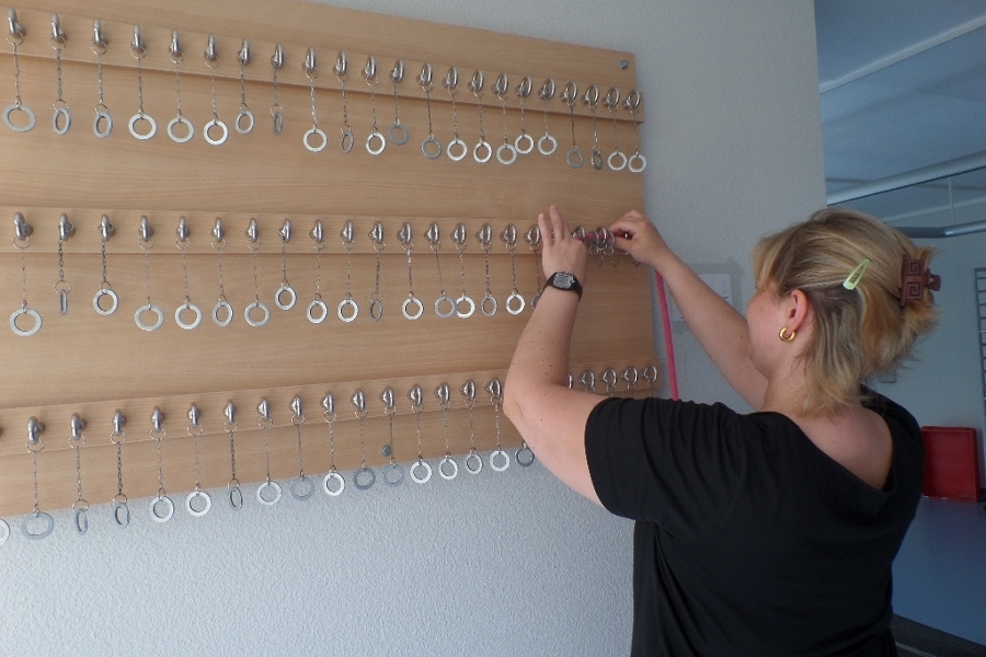 Eine Frau fedelt eine Schnur durch Löcher an einer Wand. Eine Frau fedelt eine Schnur durch Löcher an einer Wand.